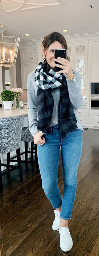 Alysia wearing a gray sweater, blue jeans, white sneakers, and a black and white plaid scarf