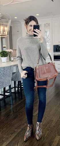 Alysia wearing gray sweater, dark blue jeans, snake print boots, and a brown handbag