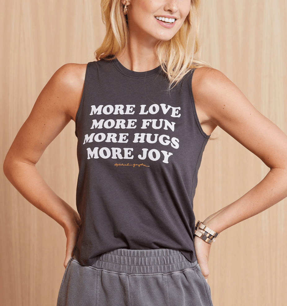 Model wearing gray tank top with white writing that says "More love, more fun, more hugs, more joy"