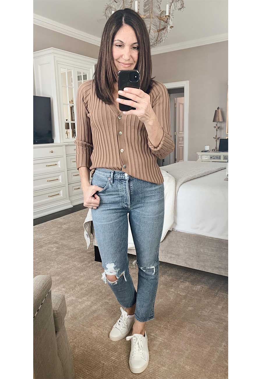 Alysia wearing a brown sweater and distressed jeans with white sneakers